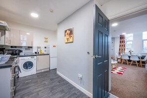 A compact kitchen with modern appliances, a dining area with a table and chairs, and a door leading to another room. - *F18GH* For relaxed & Cosy stay/Free Parking/WiFi (West Yorkshire)