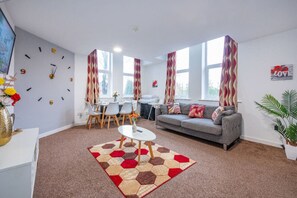 A living room with a sofa, a coffee table, a dining table with chairs, and a large window. - *F18GH* For relaxed & Cosy stay/Free Parking/WiFi (West Yorkshire)