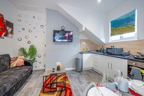 A modern living room with a sofa, TV, and a dining area with a table set for two. - *F1kr* For your relaxed & Cosy stay + Parking (Burley)