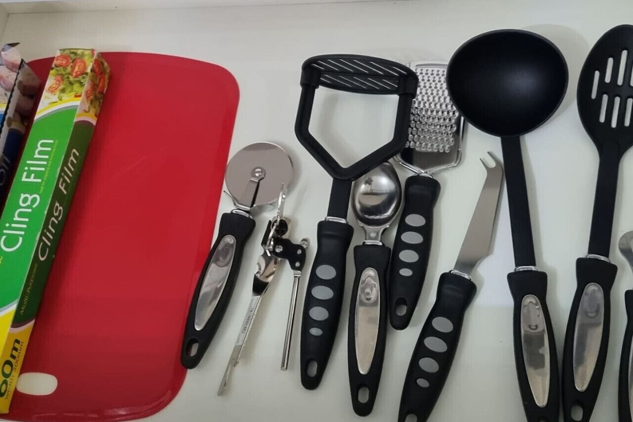 A kitchen with various utensils, a red cutting board, and a book titled 'Cling Film'.