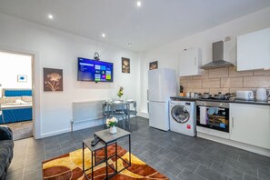 A modern kitchen with a built-in oven, a washing machine, and a flat-screen TV mounted on the wall. - *372kr* For your relaxed & Cosy stay + Parking (Burley)