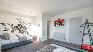 Une chambre d’hôtel moderne équipée d’un lit, d’un canapé, d’un téléviseur fixé au mur et d’une échelle.