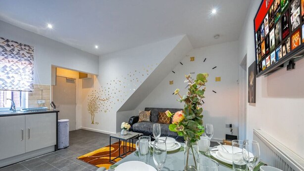 Une cuisine moderne avec un coin repas, un canapé et un mur décoratif orné de motifs géométriques.