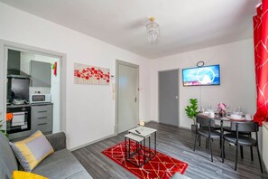 A modern living room with a grey sofa, a small table, a red rug, a TV, and a dining area with chairs and a table. - *F6*GH* Setup for your most rela (West Yorkshire)