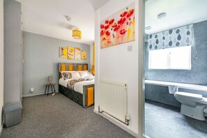 Un dormitorio con cama, un radiador, una ventana y un baño con inodoro y ducha.
