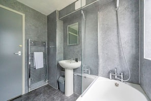 Un baño moderno con un lavabo blanco, una cabina de ducha de vidrio y un perchero para toallas.