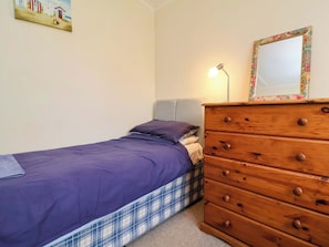 A bedroom with a bed, a dresser, a lamp, and a painting on the wall. - Sea Breeze (Bideford)