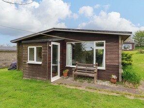 Ein kleines Holzhaus mit Veranda, einer Tür und einem Fenster.