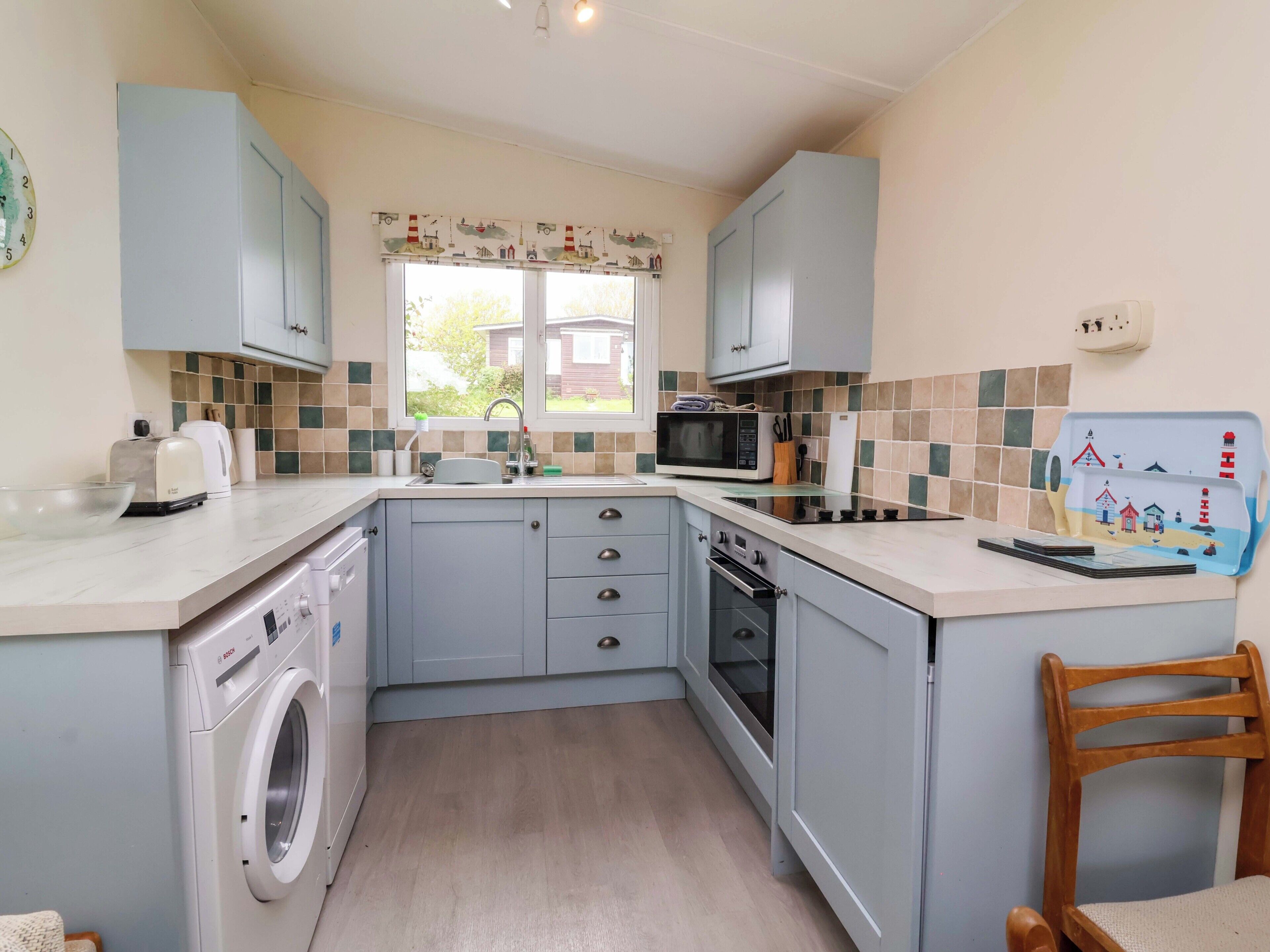 A compact kitchen with a washing machine, microwave, and sink.