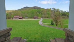 Ländliche Landschaft mit einer Straße, zwei Gebäuden und einem Hügel.