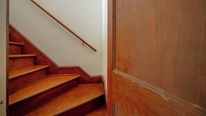 Eine Holztreppe mit Handlauf, die zu einer geschlossenen Holztür führt.