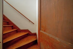 Uma escada de madeira com corrimão que leva a uma porta de madeira fechada.