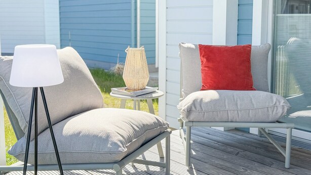 A deck with two chairs, one with a red pillow, and a floor lamp. - Funk Unit - terrace, fireplace, ground floor, washing machine, private parking (Olpenitz)