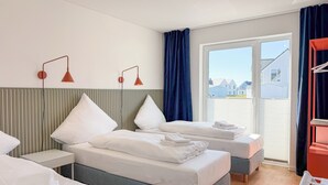 A hotel room with two beds, a nightstand, a desk, a chair, and a view of the outside. - Funk Unit - terrace, fireplace, ground floor, washing machine, private parking (Olpenitz)
