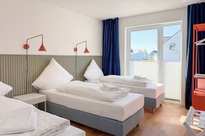 Ein Hotelzimmer mit zwei Betten, einem Nachttisch, einem Schreibtisch, einem Stuhl und Blick ins Freie.
