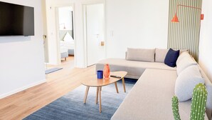 A modern living room with a sofa, a coffee table, a TV, and a cactus. - Funk Unit - terrace, fireplace, ground floor, washing machine, private parking (Olpenitz)