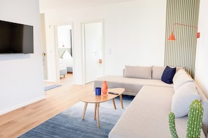 Ein modernes Wohnzimmer mit einer Couch, einem Couchtisch, einem Fernseher und einem Kaktus.