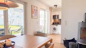 A modern kitchen with a built-in oven, a washing machine, and a dining area with a table and chairs. - Funk Unit - terrace, fireplace, ground floor, washing machine, private parking (Olpenitz)