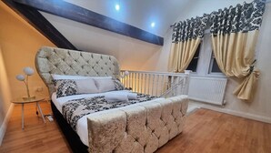 A bedroom with a tufted headboard, a bed with patterned bedding, a small round table, and a window with curtains. - *G11H* for a cosy luxurious lovely stay + Free Parking + Free Fast WiFi perfect for work or pleasure (West Yorkshire)