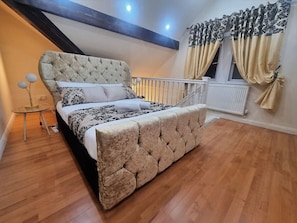 A bedroom with a tufted headboard, a bed with patterned bedding, a small round table, and a window with curtains. - *G11H* for a cosy luxurious lovely stay + Free Parking + Free Fast WiFi perfect for work or pleasure (West Yorkshire)