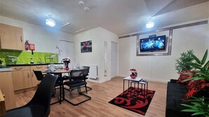 A modern living room with a dining area, a flat-screen TV mounted on the wall, and a potted plant. - *G11H* for a cosy luxurious lovely stay + Free Parking + Free Fast WiFi perfect for work or pleasure (West Yorkshire)