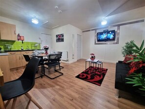 A modern living room with a dining area, a flat-screen TV mounted on the wall, and a potted plant. - *G11H* for a cosy luxurious lovely stay + Free Parking + Free Fast WiFi perfect for work or pleasure (West Yorkshire)