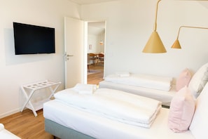 A hotel room with two beds, a TV, a drying rack, and a dining area visible through an open door. - Tower of Power – Balcony, Fireplace, Upper Floor, Washing Machine, Private Parki (Olpenitz)