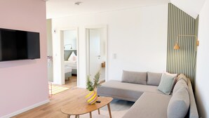 Una sala de estar moderna con un televisor de pantalla plana, un sofá, una mesa de centro y una pared a rayas.