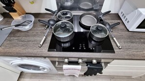 Une cuisine équipée d’une cuisinière intégrée, de casseroles, de poêles, d’un four à micro-ondes et d’un lave-linge.