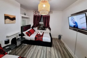 Une chambre d’hôtel moderne équipée d’un lit, d’une télévision, d’une petite table et d’un élément décoratif mural.