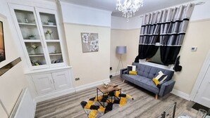 Un salon comprenant un canapé, une table basse, un lustre et un coin repas avec des chaises et une table.
