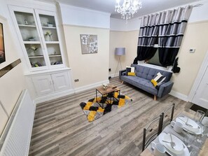 A living room with a sofa, a coffee table, a chandelier, and a dining area with chairs and a table. - *6R*your most amazing & relaxed stay + Free Parking + Free Fast WiFi * (Holbeck)