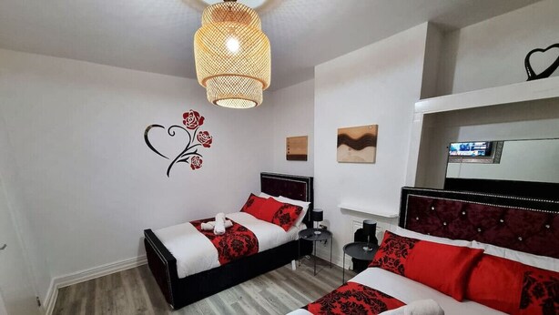 Une chambre d’hôtel avec deux lits, un luminaire au plafond, une horloge murale et une petite table.