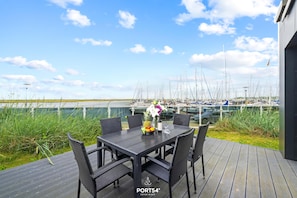A deck with a table and chairs, overlooking a marina with boats. - Küstenbrise holiday flat in Marina Wendtorf with sea views & 159 m² for up to 12 (Wendtorf)