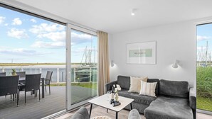 Een moderne woonkamer met een bank, een salontafel en uitzicht op een jachthaven.
