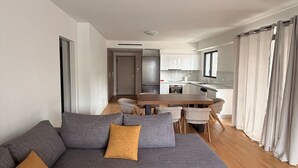 A modern living room with a grey sectional sofa, a small coffee table, and a remote control on the floor. - Alimos Urban Retreat (Alimos)
