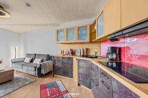 Eine moderne Küche mit grauen Schränken, einer roten Spritzschutzwand und einem eingebauten Backofen.