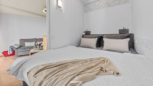 Un dormitorio moderno con una cama grande, una mesita de noche, una lámpara y vistas al área de estar.