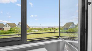 Una habitación con un amplio ventanal que da a un espacio verde con casas.