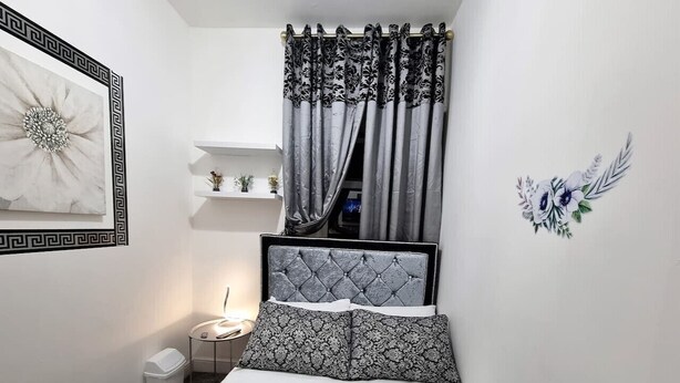 Un dormitorio pequeño y ordenado con cama, mesita de noche y tocador.