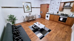 Un espacio habitable compacto con sofá, mesa de comedor y kitchenette.