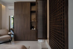 A modern room with a sofa, a wooden cabinet, and a decorative wooden screen. - Riviera Boutique Hotel (Ubud)