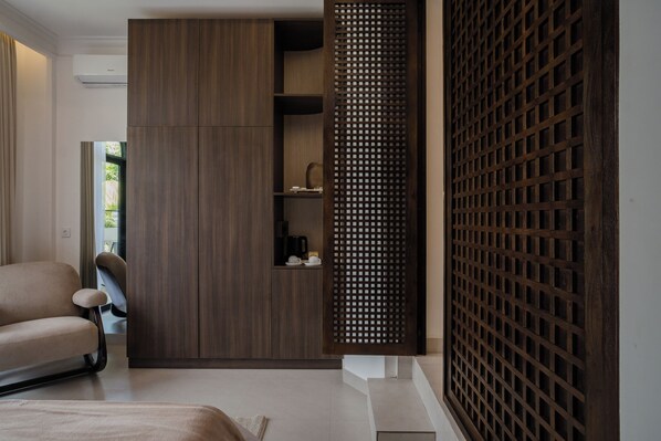A modern room with a sofa, a wooden cabinet, and a decorative wooden screen. - Riviera Boutique Hotel (Ubud)