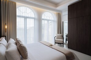A hotel room with a large bed, a chair, and a wardrobe. - Riviera Boutique Hotel (Ubud)