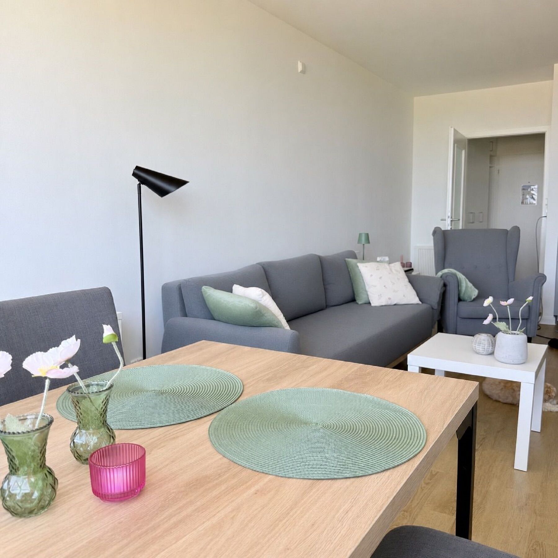 A modern living room with a grey sofa, a wooden coffee table, and a white side table.