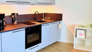 Een moderne keuken met witte kastjes, een zwarte vaatwasser en een inbouwoven.