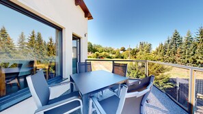 Een balkon met een tafel en stoelen, met uitzicht op een bebost gebied.