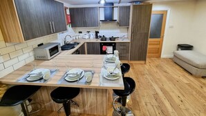 Una cocina moderna con una isla central, armarios de madera oscura y un comedor con taburetes.