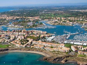An aerial view of a coastal town with a marina, residential buildings, and a beach. - Classic Studio with Balcony and Secure Parking - Capacity 2 ppl (Cap d'Agde)