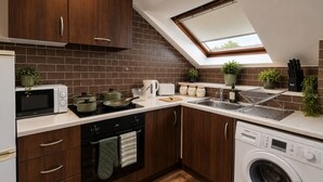 A compact kitchen with a built-in oven, microwave, and washing machine, a skylight, and wooden cabinets. - *F15GH* Setup for your most relaxed & amazing stay + Free Parking + Free Fast WiFi (West Yorkshire)
